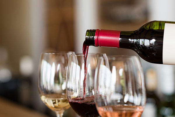 red wine poured into glass between a glass of white and rose