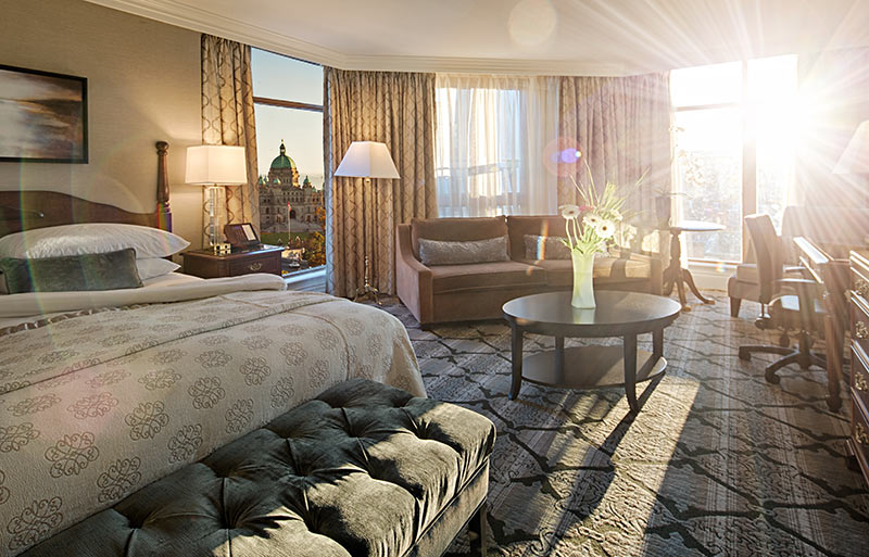 Large corner room with large windows looking over city and Parliament buildings, light pouring through windows illumination vase of flowers on table in center of room.